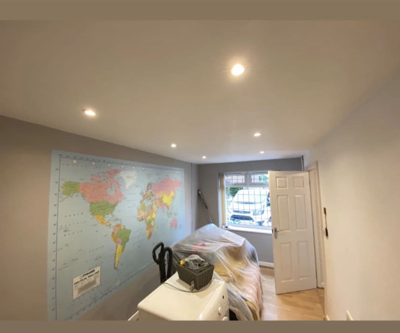 Bed sheeted over and furniture pulled to the middle, leaving the walls and skirting clear - preparing a home for a house rewire