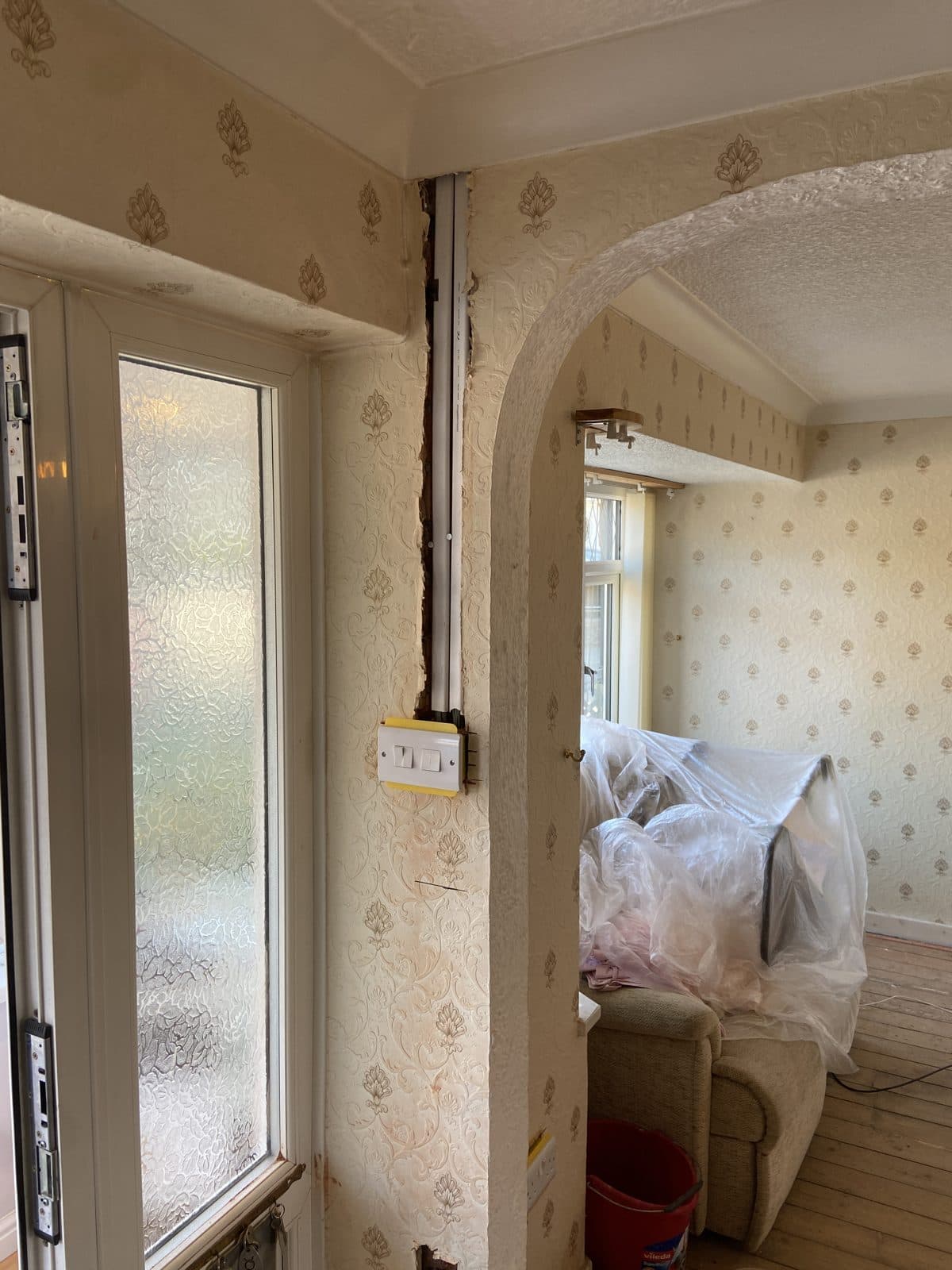 Lounge furniture pulled together and covered, walls and floor edges clear for the engineers - preparing a home for a house rewire