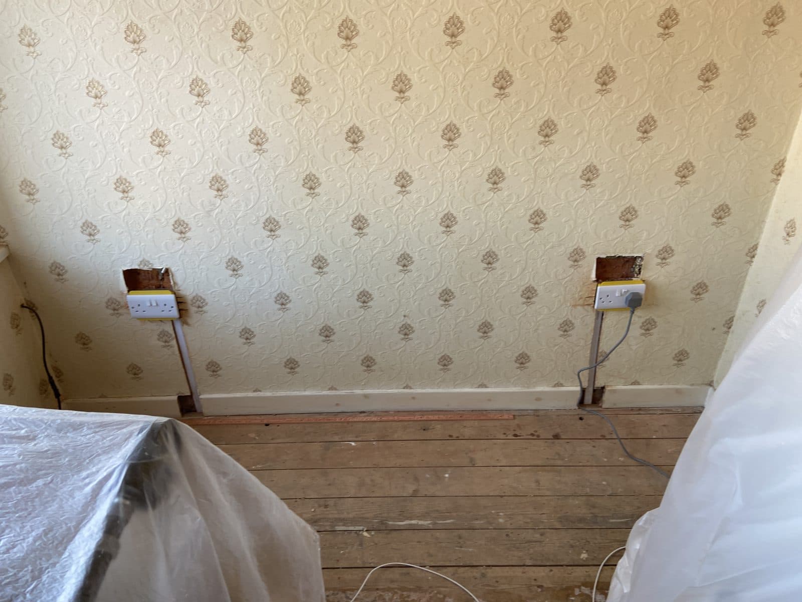Bedroom cleared to the centre and sheeted, leaving the wall and sockets free - preparing a home for a house rewire
