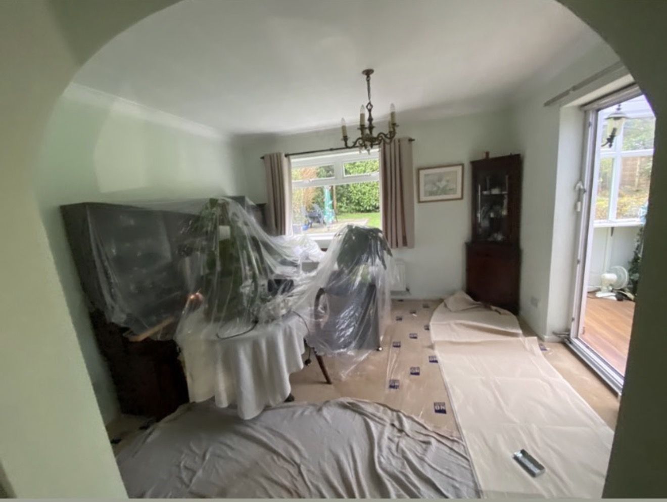 Living room furniture covered in plastic sheeting the evening before a house rewire